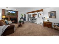 Cozy living room featuring a brick fireplace, plush carpet, and open access to the kitchen bar at 4899 S Dudley St # 3A, Littleton, CO 80123