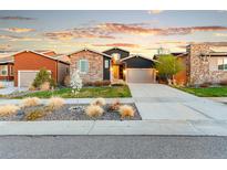 Beautiful two-story home featuring stone accents, manicured lawn, and a two-car garage at sunset at 17720 W 94Th Dr, Arvada, CO 80007