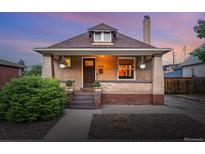 Charming brick home featuring a cozy front porch, well-manicured landscaping, and warm exterior lighting at 3928 Zuni St, Denver, CO 80211