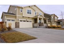 Two-story house with beige siding, stone accents, and a three-car garage at 2521 E 163Rd Pl, Thornton, CO 80602