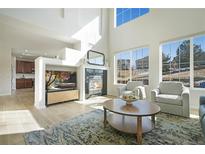 Bright living room features a fireplace, large windows, high ceilings and an area rug at 10538 Ashfield St, Highlands Ranch, CO 80126