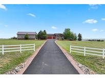 Exterior view down a driveway lined by a white fence, leading to a house and garage at 3519 Zane Gray Loop, Parker, CO 80138