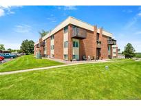 Brick apartment building with well-maintained lawn, lush greenery and a balcony at 3613 S Sheridan Blvd # 10, Denver, CO 80235