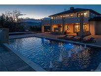 Stunning backyard pool with fountains, outdoor fireplace, lounge chairs and mountain views at twilight at 15902 W 64Th Ave, Arvada, CO 80007