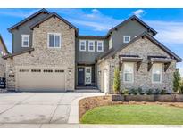 Beautiful two-story home featuring a stone facade, well-manicured lawn, and a spacious three car garage at 6677 Crossbridge Cir, Castle Rock, CO 80108