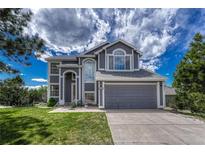 Two-story home with an attached two-car garage and a well-manicured lawn under a cloudy blue sky at 3630 Sawgrass Trl, Castle Rock, CO 80109