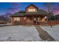 Charming home featuring a cozy front porch and beautifully landscaped front yard covered with snow at 225 Longspur Dr, Brighton, CO 80601