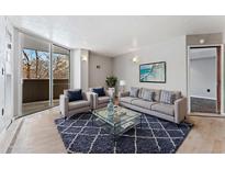 Bright living room featuring modern furnishings, stylish rug, and a sliding glass door to the balcony at 601 W 11Th Ave # 109, Denver, CO 80204
