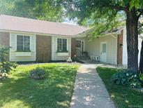 Charming single-story home featuring a lush green lawn, flower beds, and a brick facade, complemented by white trim and shutters at 1572 W Long Ave, Littleton, CO 80120