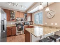 Well-lit kitchen featuring stainless steel appliances, granite countertops, and wooden cabinets at 12921 Grant W Cir # B, Thornton, CO 80241