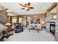 Open living room showcasing a stone fireplace and seamless flow to the kitchen at 2116 Ridgetrail Dr, Castle Rock, CO 80104