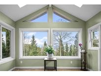 Bright sunroom with vaulted ceilings and large windows showcasing scenic views of the surrounding forest at 356 Castlewood Dr, Evergreen, CO 80439