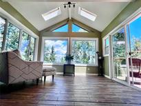 Bright sunroom features skylights, large windows with stunning views, and beautiful wood-look floors at 356 Castlewood Dr, Evergreen, CO 80439
