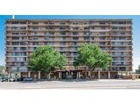 Multi-story condo building with multiple balconies and mature trees lining the front at 2225 Buchtel Blvd # 207, Denver, CO 80210