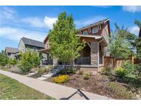 Charming two-story home featuring stone accents, a welcoming porch, and beautifully landscaped front yard at 10859 E 25Th Dr, Aurora, CO 80010