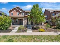 Charming two-story house boasts a welcoming porch and beautifully landscaped front yard at 10859 E 25Th Dr, Aurora, CO 80010