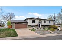 Split level home with two car garage, muted colors, landscaping, and driveway at 11165 W 58Th Ave, Arvada, CO 80002