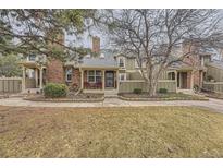 Charming townhome featuring a brick chimney, cozy front porch with two chairs, and inviting curb appeal at 7721 S Curtice Way # B, Littleton, CO 80120