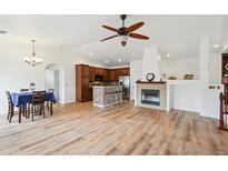 Open-concept living room with hardwood floors, a fireplace, and a ceiling fan for a bright and airy feel at 7777 E 23Rd Ave # 203, Denver, CO 80238