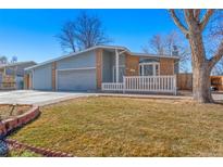 Charming single Gathering house with blue sidings, brick accents, a gray garage door, and a well-manicured lawn at 1027 Norfolk St, Aurora, CO 80011