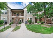 Inviting multi-level home featuring well-maintained landscaping, stone accents, and wooden stairways to upper units at 3952 S Carson St # 103, Aurora, CO 80014