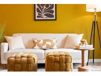 Comfortable living room featuring a white sofa, gold ottoman, and trendy decor at 1820 Newland Ct # 310, Lakewood, CO 80214