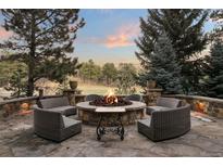Stone patio boasts a cozy fire pit with comfortable wicker seating, perfect for outdoor gatherings at 77 Comstock Pl, Castle Rock, CO 80108