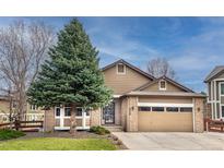 Charming exterior elevation features brick and siding, a mature tree, and attached two-car garage at 6118 Salvia Ct, Arvada, CO 80403