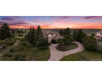 Charming two-story home with mature trees and a circular driveway at sunset at 5855 Saddle Creek Trl, Parker, CO 80134