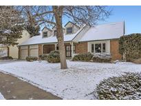 Charming brick home featuring dormer windows, a covered porch, and a snow-covered yard at 5938 E Weaver Cir, Centennial, CO 80111