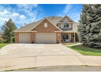 Charming two-story home featuring a brick facade, three-car garage, and a well-manicured front lawn at 7472 S Utica St, Littleton, CO 80128