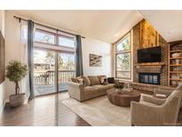 Inviting living room features a cozy fireplace, deck access, and large windows providing ample natural light at 8159 Lodgepole Trl, Lone Tree, CO 80124