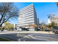 Exterior view of a modern high-rise building with a glass entrance and surrounding landscaping on a sunny day at 789 N Clarkson St # 906, Denver, CO 80218