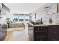 Open concept living area featuring hardwood floors, large windows with city views, and a modern kitchen at 789 N Clarkson St # 906, Denver, CO 80218