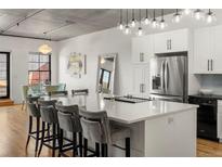Modern kitchen features a large island, stainless steel appliances, and sleek white cabinetry at 1499 Blake St # 3M, Denver, CO 80202