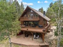 Stunning exterior view of a brown two-story home surrounded by lush trees, featuring multiple decks and outdoor living spaces at 32462 Lodgepole Dr, Evergreen, CO 80439