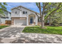 Charming two-story home boasts a brick facade, attached garage, and a welcoming front porch with a blue front door at 5260 Morning Glory Pl, Highlands Ranch, CO 80130