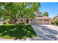 Charming two-story home with a three-car garage, a landscaped front yard, and a large shade tree at 9673 Pinebrook St, Highlands Ranch, CO 80130