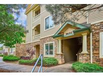 Beautiful condo exterior featuring stone accents, tan siding, and landscaped grounds at 9692 W Coco Cir # 103, Littleton, CO 80128