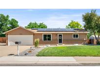 Charming single-story home featuring a well-manicured lawn, and solar panels on the roof at 6353 W 78Th Ave, Arvada, CO 80003