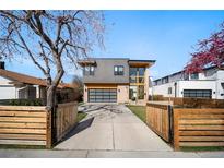 Contemporary two-story home with mixed materials, a driveway, modern garage door and a partially fenced front yard at 3485 S Clermont St, Denver, CO 80222