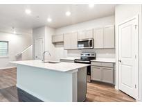 Bright kitchen with an island, modern appliances, and gray cabinetry at 18998 E 94Th Pl, Commerce City, CO 80022