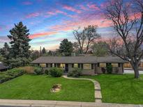 Charming single-story home with a manicured front lawn, stone pathway, and mature trees creating a welcoming curb appeal at 180 Dover St, Lakewood, CO 80226