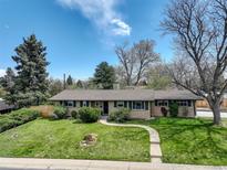 Charming single-story home with a well-maintained front lawn and mature trees on a beautiful day at 180 Dover St, Lakewood, CO 80226