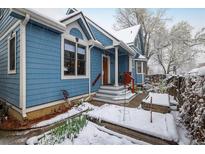 Charming blue home with snow-covered yard and inviting front porch and stairway at 1605 17Th St, Boulder, CO 80302