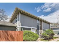 Two-story home with gray siding, stone accent column, and manicured landscaping at 10001 E Evans Ave # 74C, Aurora, CO 80247