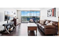 Bright living room featuring hardwood floors, a leather sofa and balcony with city views at 1155 N Ash St # 1408, Denver, CO 80220