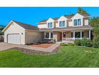 Charming two-story home with a well-manicured lawn, brick accents, and an inviting front porch seating area at 8000 S Williams Way, Centennial, CO 80122