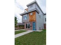 Modern home boasts a blue door, brick accents, stylish wood, and a lush lawn at 1355 Zenobia St, Denver, CO 80204