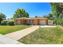 Charming single-story brick home features a well-manicured lawn, long driveway, and attached garage at 3354 W Arlington Ave, Littleton, CO 80123